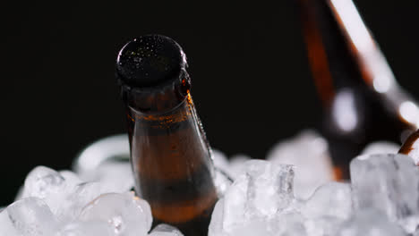Nahaufnahme-Von-Glasflaschen-Mit-Kaltem-Bier-Oder-Alkoholfreien-Getränken,-Die-In-Einem-Mit-Eis-Gefüllten-Eimer-Vor-Schwarzem-Hintergrund-Kühlen-3
